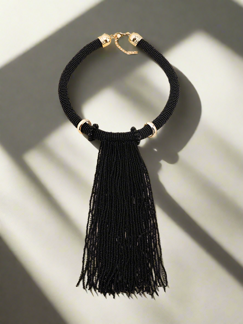 Elegant handmade black beaded tassel necklace with gold-tone accents, featuring a bold statement design perfect for evening wear and special occasions.