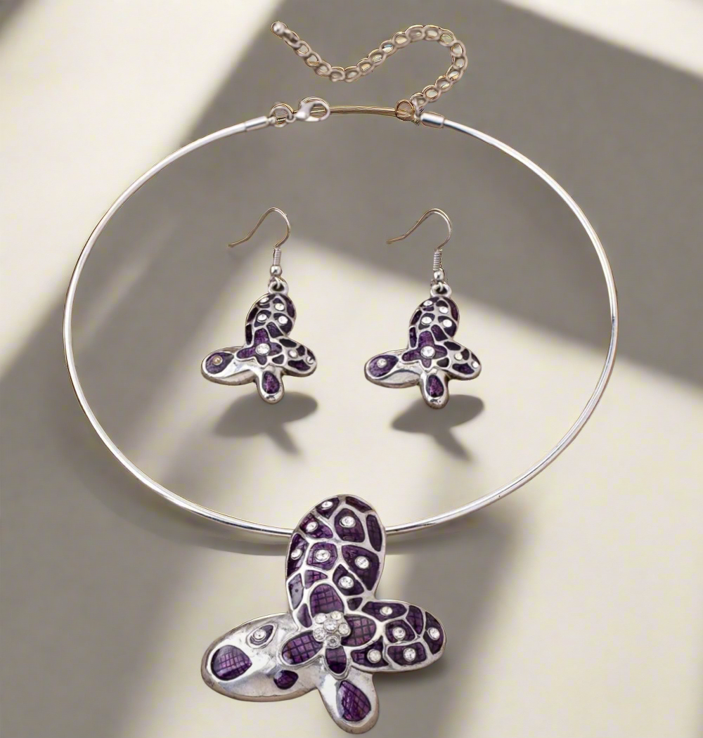 Silver choker and earring set featuring purple butterfly pendants with rhinestone accents displayed on a black bust stand.