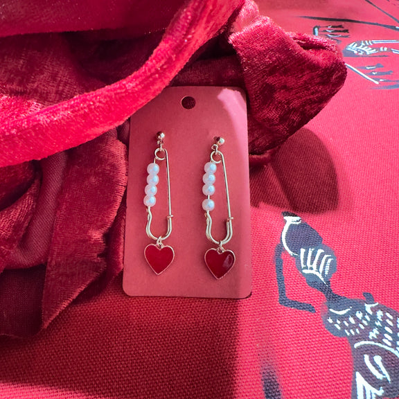 Gold-plated dangle earrings with white beads and red heart charmd for Valentine’s Day or special occasions.