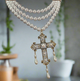 Multi-strand pearl choker necklace with ornate gold filigree cross pendant featuring faux pearls and teardrop pearl drops, elegant and vintage style.