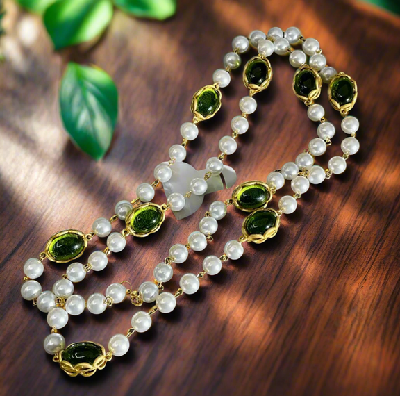 Long layered necklace featuring alternating white pearl beads and oval green gemstones framed in gold-tone settings, displayed on a black velvet bust. The necklace can be worn as a single long strand or wrapped into a double-layered style.