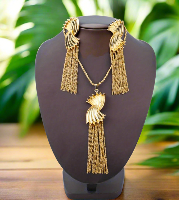 Gold fan-shaped statement earrings with cascading gold mesh tassels displayed on a white background with black text