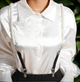Pearl and black suspender straps clipped to black pants and styled over a white satin blouse for a modern, elegant look.