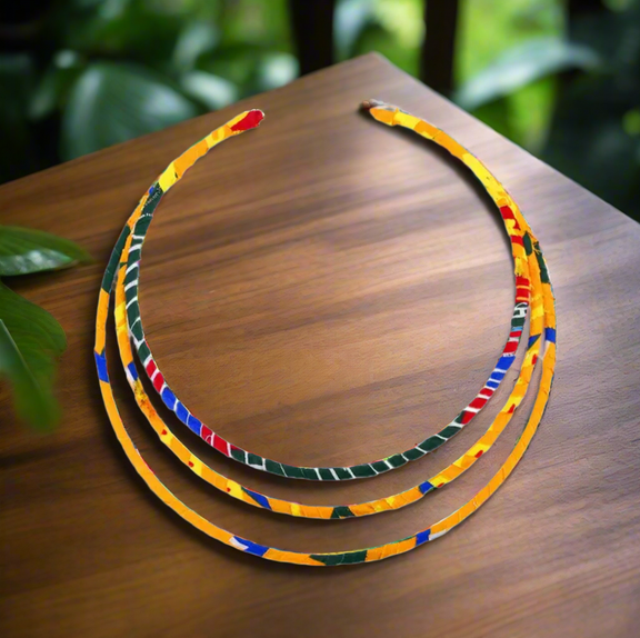 Ankara fabric-wrapped triple-strand necklace in bold red, yellow, green, and blue with matching round African print button earrings displayed on a black bust stand.