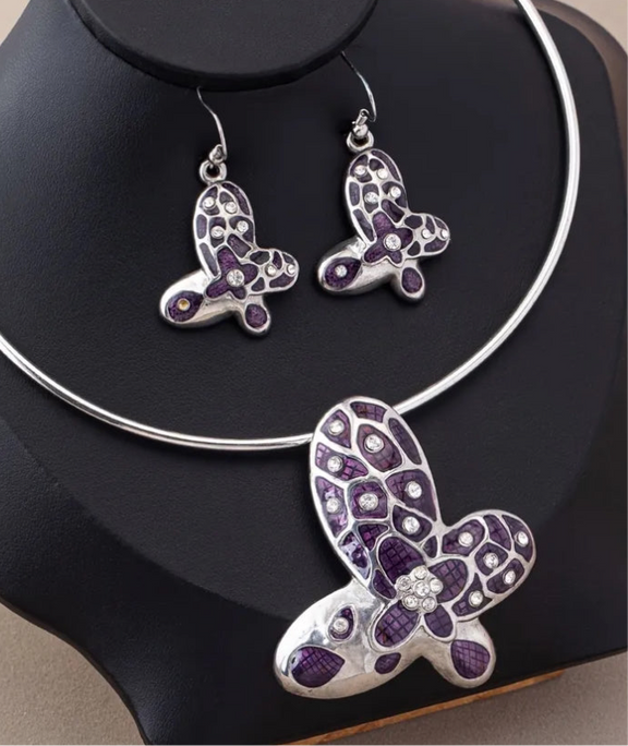 Silver choker and earring set featuring purple butterfly pendants with rhinestone accents displayed on a black bust stand.