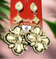 Gold-tone drop earrings featuring a floral-inspired design with faux pearls and rhinestones, displayed on a black mannequin head.