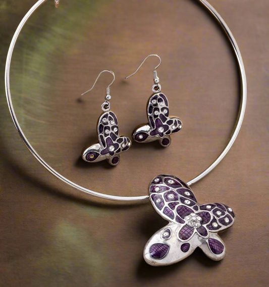 Silver choker and earring set featuring purple butterfly pendants with rhinestone accents displayed on a black bust stand.