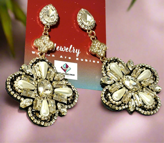 Gold-tone drop earrings featuring a floral-inspired design with faux pearls and rhinestones, displayed on a black mannequin head.