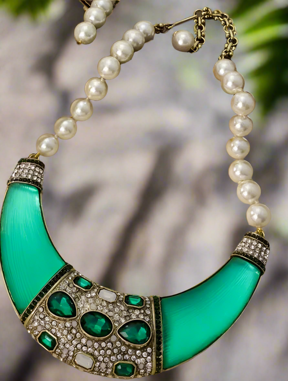 Bold green gemstone and pearl statement necklace with crystal detailing and crescent-shaped collar on vintage tray