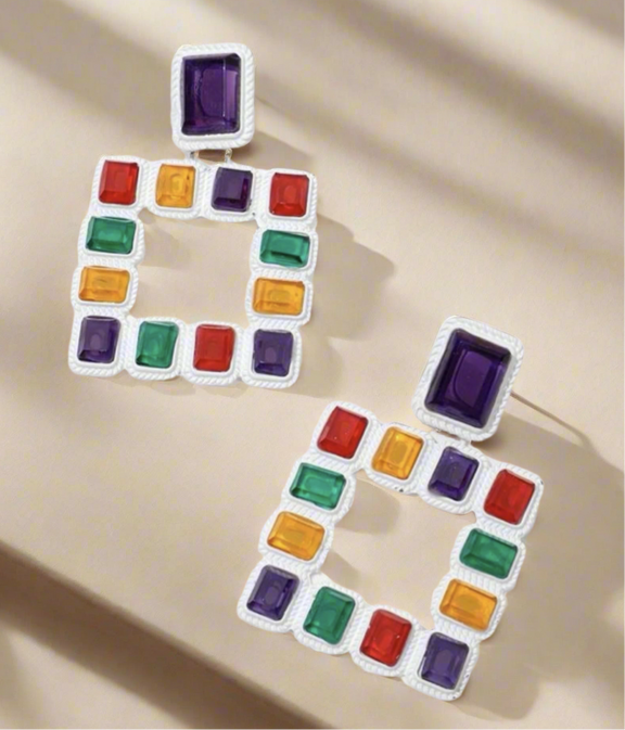 Vibrant geometric square earrings featuring multicolored red, green, purple, and yellow gemstones set in a textured white frame – a bold statement accessory