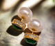 Double-sided stud earrings with emerald front stone and pearl backing on satin background