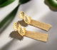 Gold fan-shaped statement earrings with cascading gold mesh tassels displayed on a white background with black text