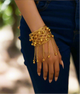 Gold-tone lattice cuff bracelet with dangling chain and bell charms, elegant statement jewelry for women, bold arm cuff with jingling accents.