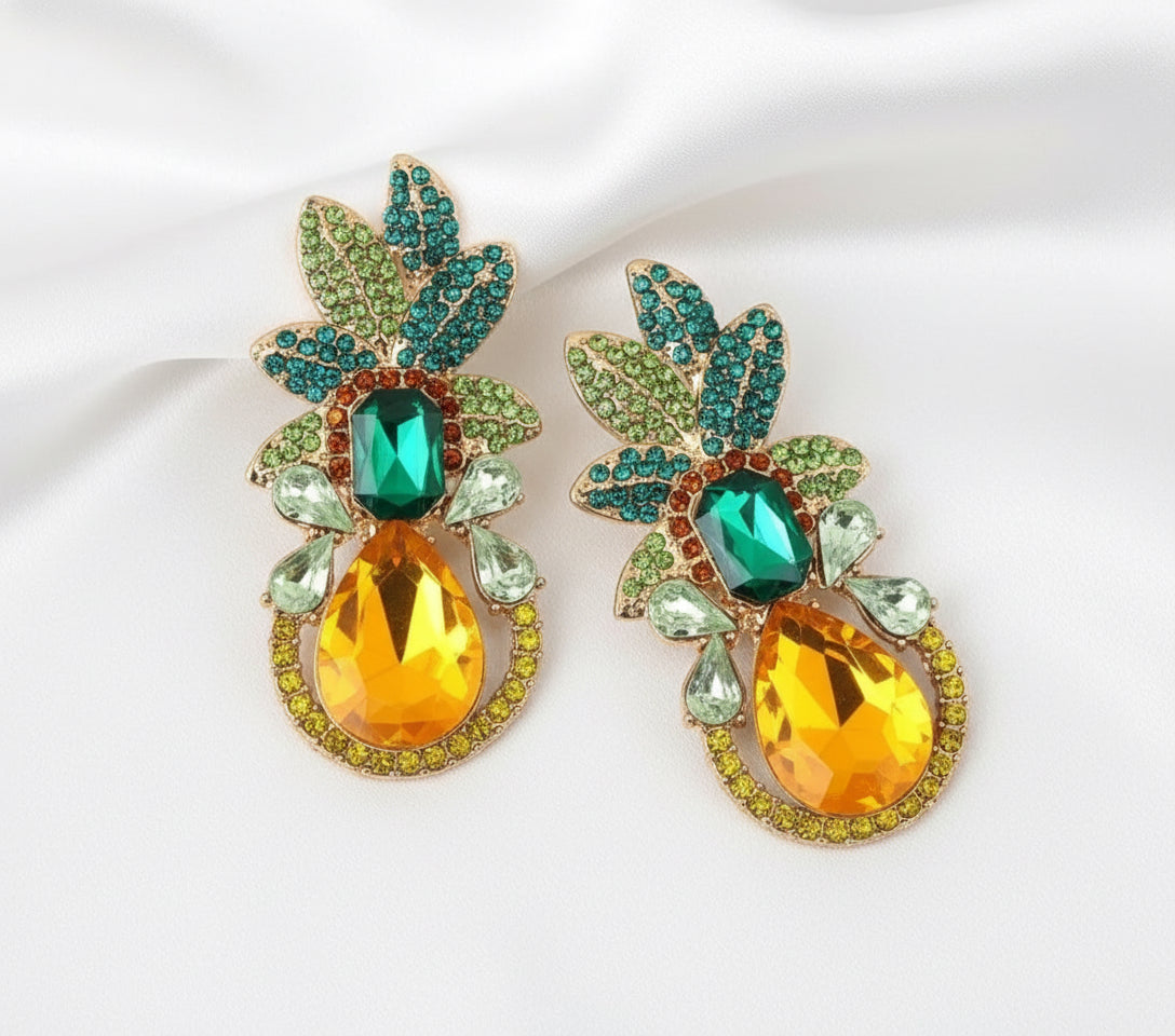 Pair of ornate earrings with green and orange gemstones on a white background