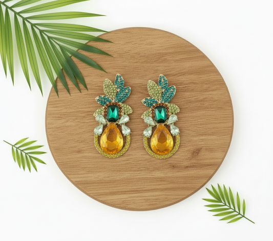 Pair of earrings with green and orange stones on a gold stand against a white background