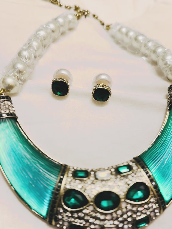 Bold green gemstone and pearl statement necklace with crystal detailing and crescent-shaped collar on vintage tray