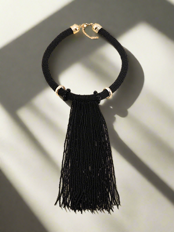 Elegant handmade black beaded tassel necklace with gold-tone accents, featuring a bold statement design perfect for evening wear and special occasions.