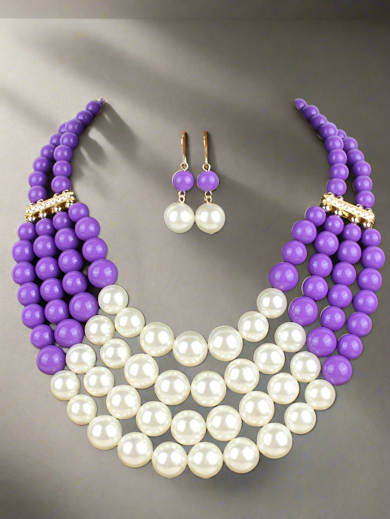 A luxurious layered necklace featuring rich purple beads and classic white pearls, paired with matching drop earrings. A statement jewelry set fit for a queen, perfect for elegant occasions and everyday glam.