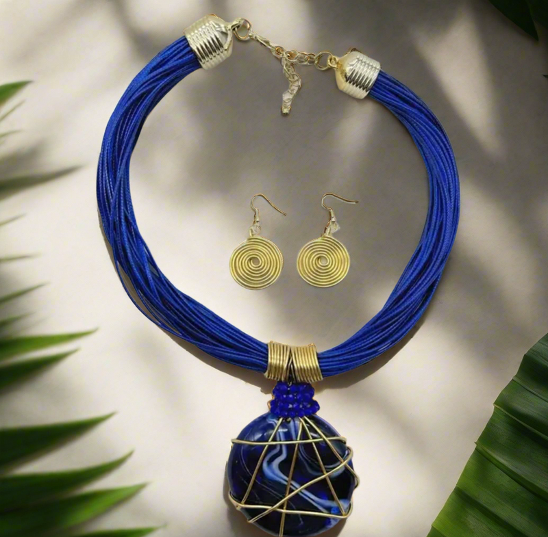 Bold African-inspired amber resin necklace wrapped in gold wire, featuring brown layered cords and matching gold coil earrings, handcrafted jewelry for women.