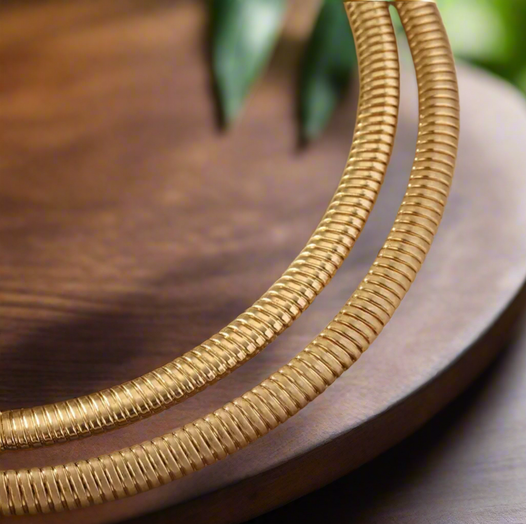 Gold statement necklace with large 2.5-inch disc pendant and 14-inch collar chain with extender on satin background