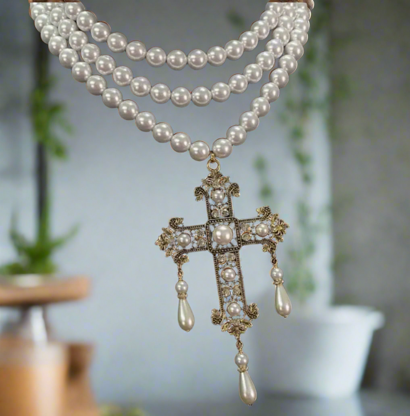 Multi-strand pearl choker necklace with ornate gold filigree cross pendant featuring faux pearls and teardrop pearl drops, elegant and vintage style.
