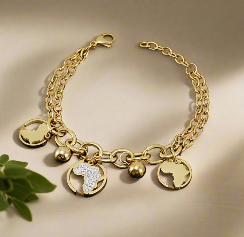 “Gold Africa charm bracelet with double link chain, gold map cutouts, rhinestone accents, and polished gold spheres, displayed on a white background.”
