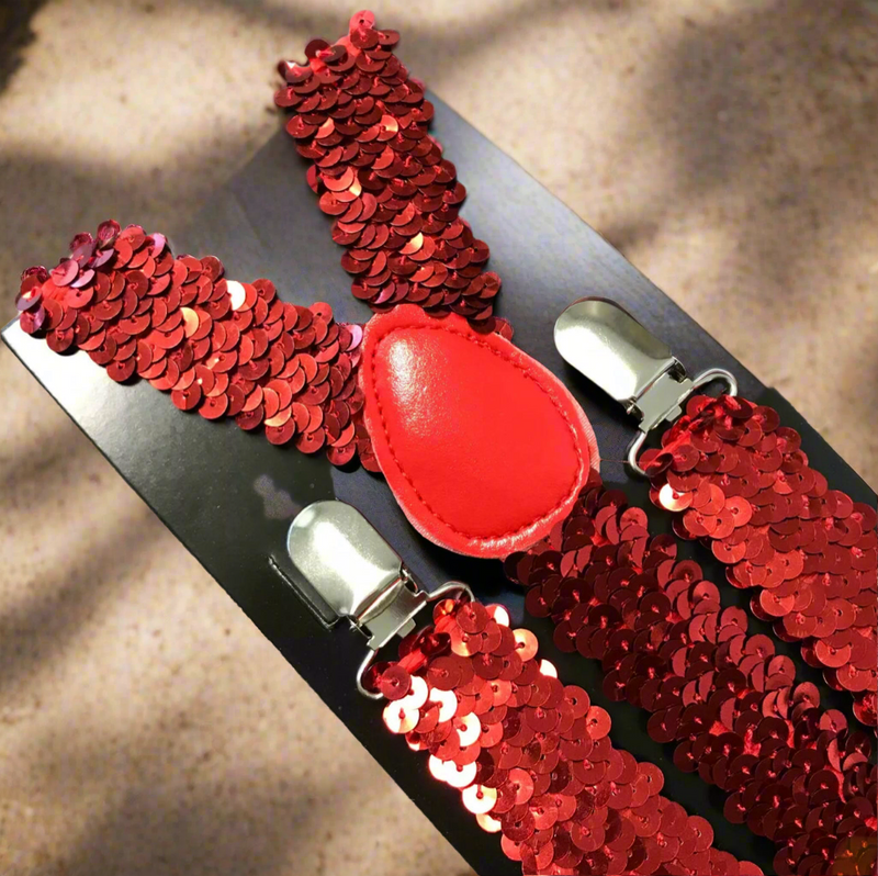 Red sequin suspenders with Y-back design and silver clips displayed on a light wooden surface.