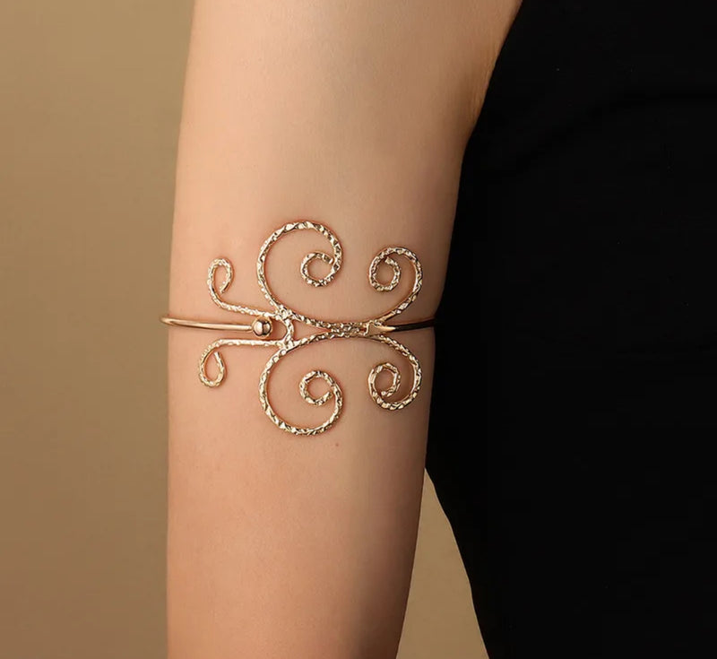 Gold-tone floral and swirl upper arm cuff for women, adjustable open bangle with petal and spiral design, boho chic statement arm jewelry.
