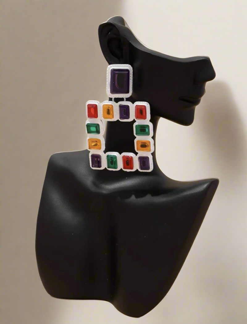 Vibrant geometric square earrings featuring multicolored red, green, purple, and yellow gemstones set in a textured white frame – a bold statement accessory