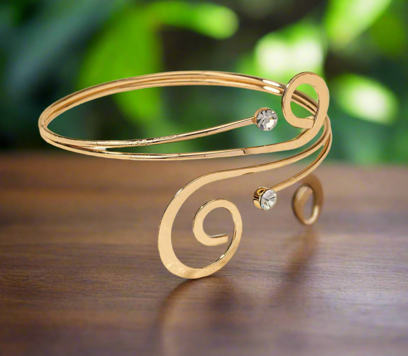 Minimalist gold-tone spiral arm cuff bracelet with crystal accents, elegant open bangle for women, adjustable and lightweight.

