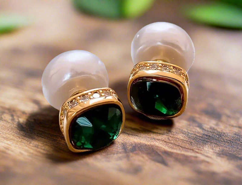 Double-sided stud earrings with emerald front stone and pearl backing on satin background