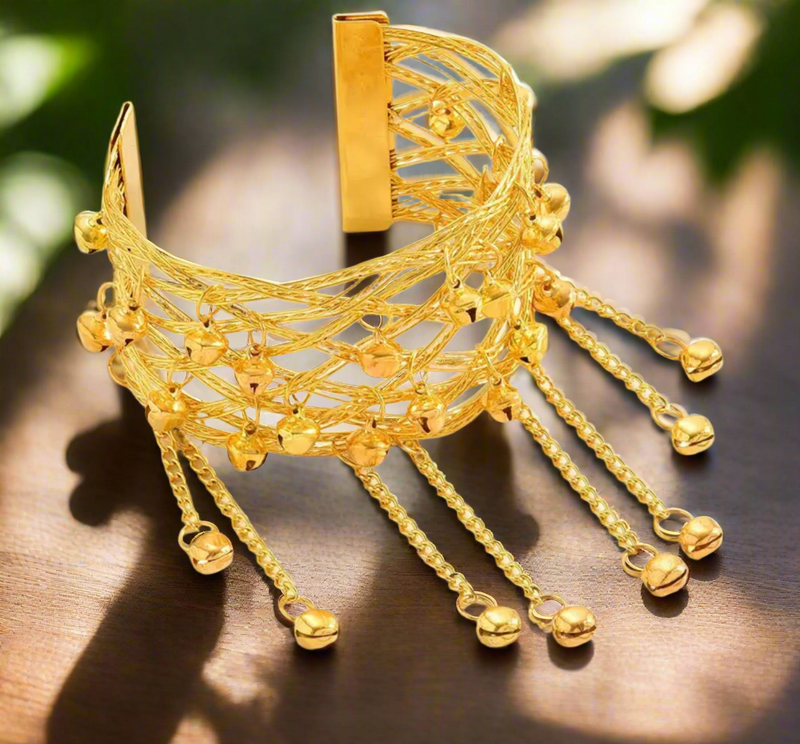 Gold-tone lattice cuff bracelet with dangling chain and bell charms, elegant statement jewelry for women, bold arm cuff with jingling accents.