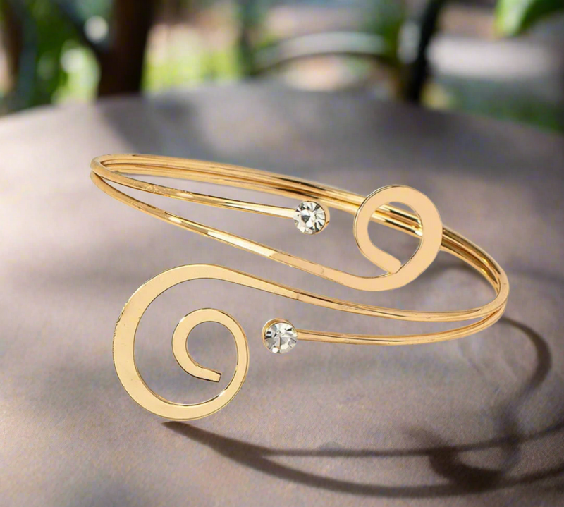 Minimalist gold-tone spiral arm cuff bracelet with crystal accents, elegant open bangle for women, adjustable and lightweight.
