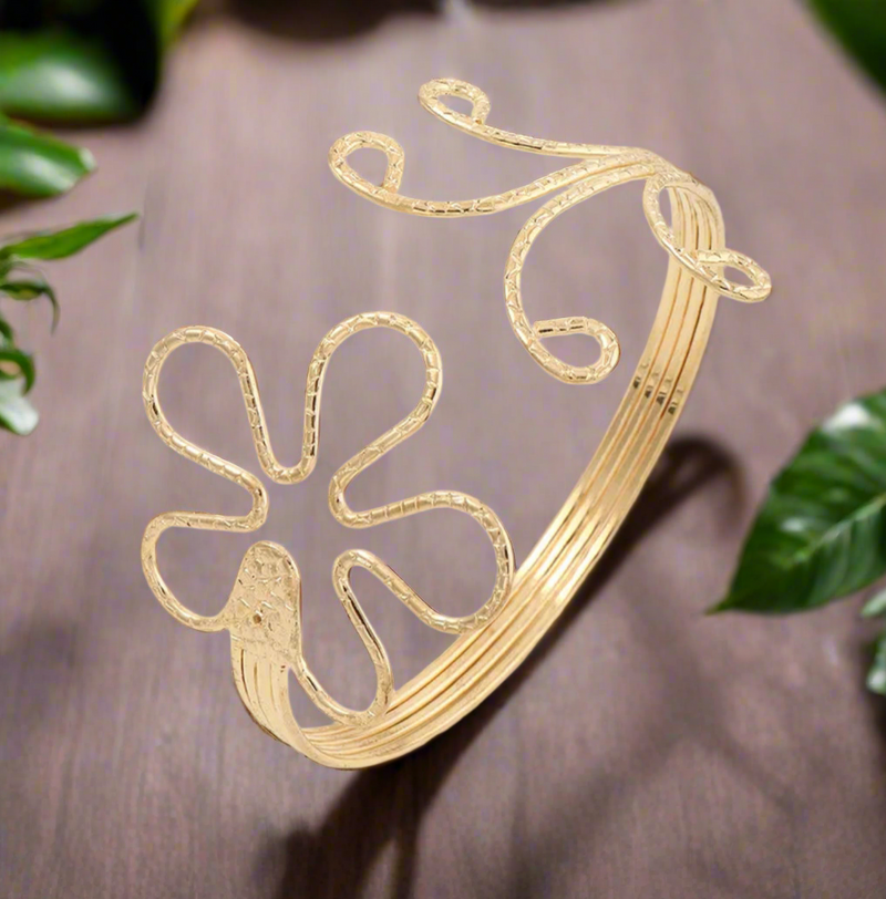 Gold-tone floral and swirl upper arm cuff for women, adjustable open bangle with petal and spiral design, boho chic statement arm jewelry.
