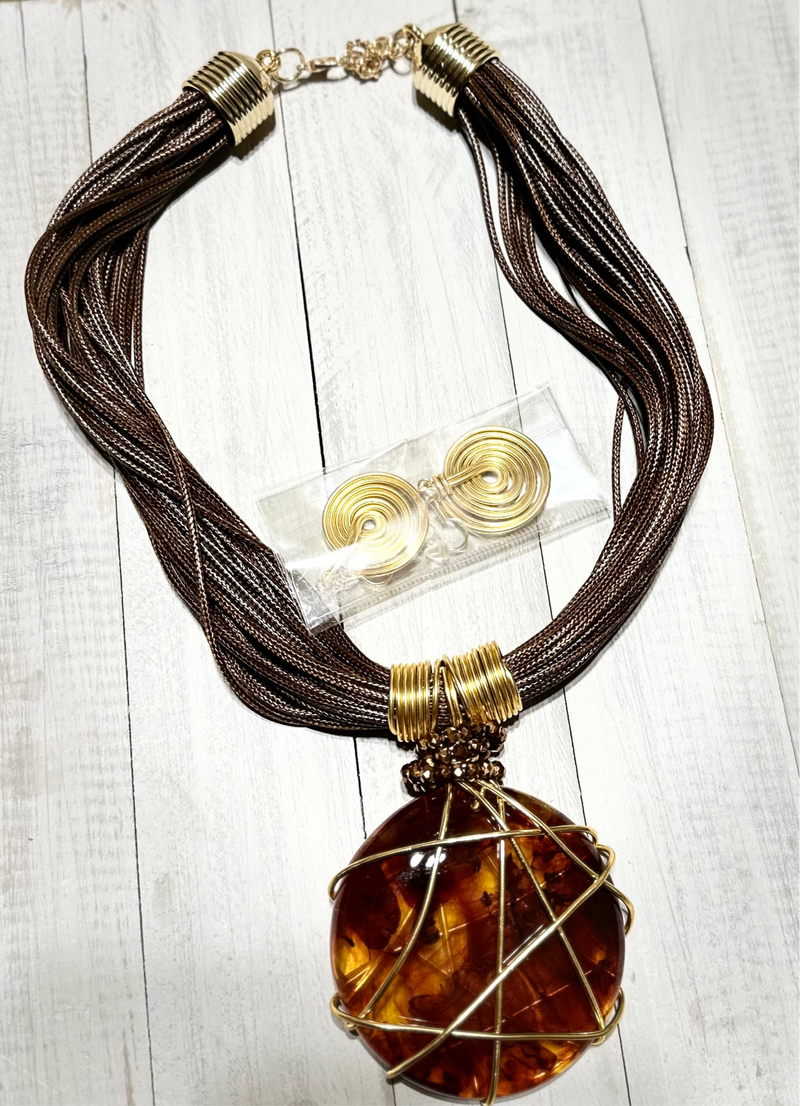 Bold African-inspired amber resin necklace wrapped in gold wire, featuring brown layered cords and matching gold coil earrings, handcrafted jewelry for women.