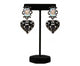 Black heart-shaped statement earrings with iridescent crystal tops, placed on a neutral stone background. Elegant jewelry from Women Are Rubies.