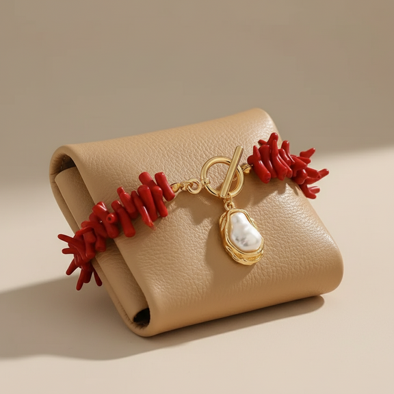 Beige leather clutch with red coral and gold charm on a beige background