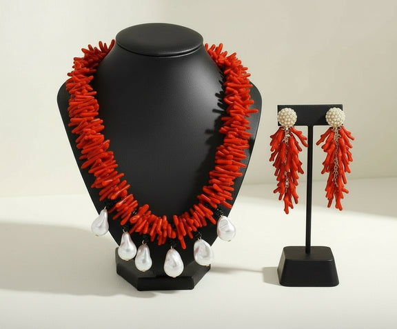 Red coral necklace and earrings on black stands against a beige background