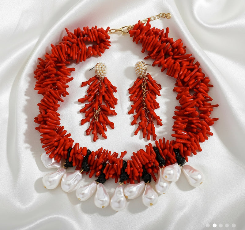 Red coral necklace and earrings set on a white fabric background
