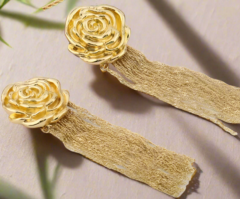 Gold rose-shaped earrings with cascading chain tassels, displayed on a white background with black text