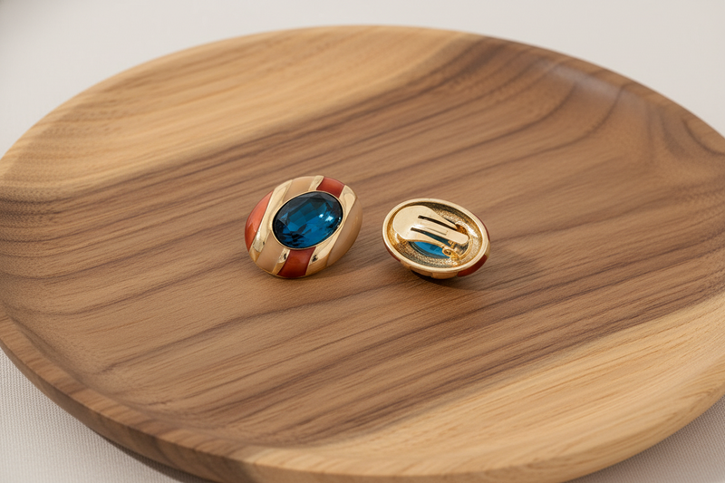 Gold earrings with blue gemstones on a wooden surface