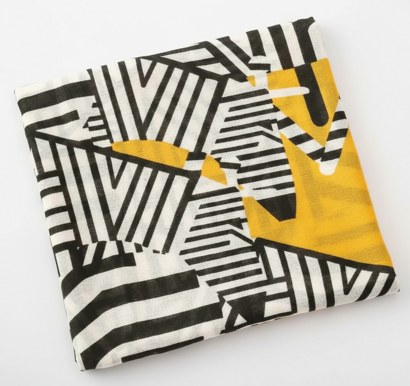 This lightweight piece features a striking mustard yellow base accented by black and white geometric patterns, creating a perfect balance between warmth and sophistication.