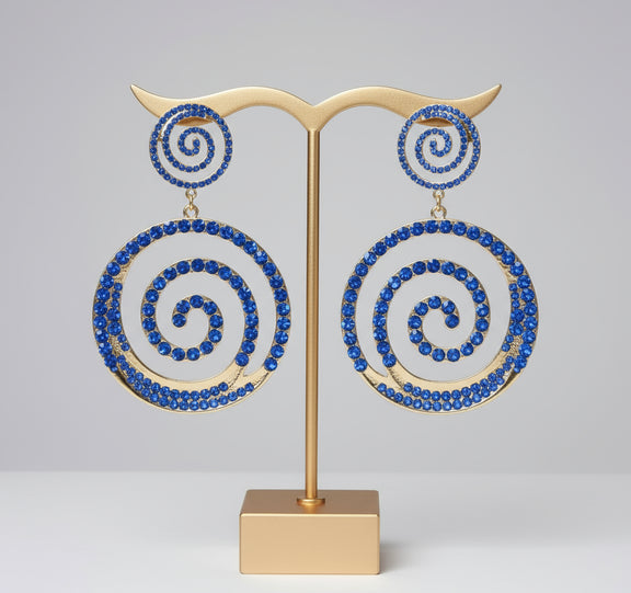 Spiral earrings with blue stones on a black mannequin ear