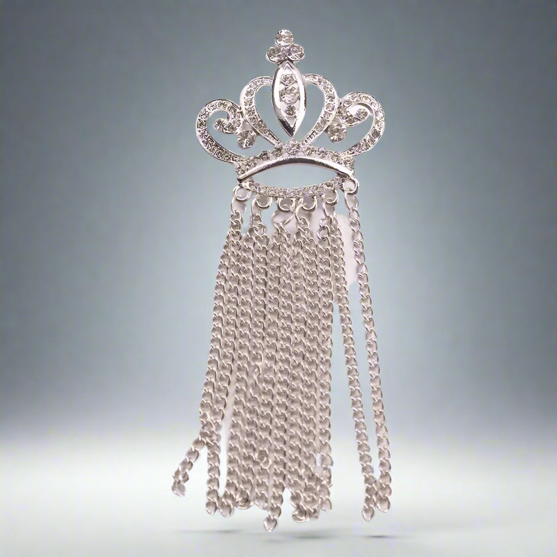 The Otre Rive Silver Tassel Brooch by Desiree W.A.R Store is a silver crown brooch featuring sparkling rhinestones and cascading chain tassels.