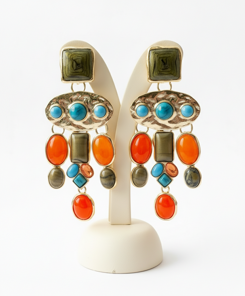 Colorful earrings with turquoise, orange, and green stones on a white stand.