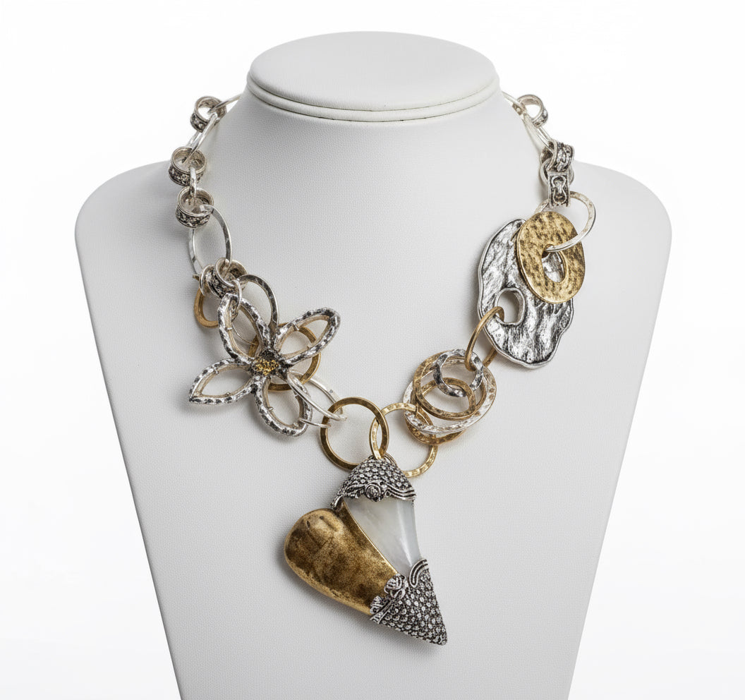 Statement mixed-metal heart necklace featuring textured gold and silver links with a bold artistic pendant.