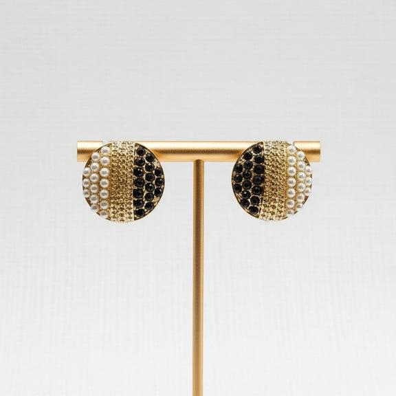 Gold earrings with black and pearl accents in a jewelry box