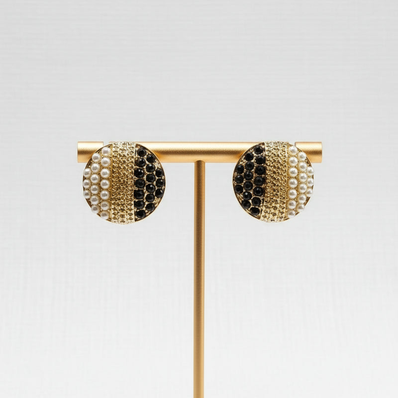 Gold earrings with black and pearl accents in a jewelry box