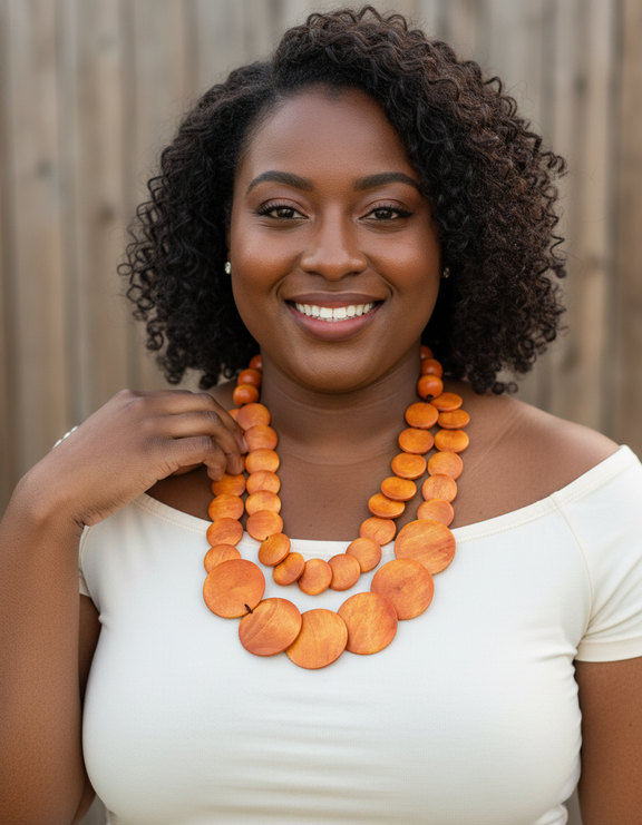 Double-strand orange wooden bead necklace with circular discs, displayed on rustic wooden background.
