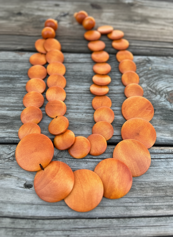 Necklace with orange circular beads on a wooden surface